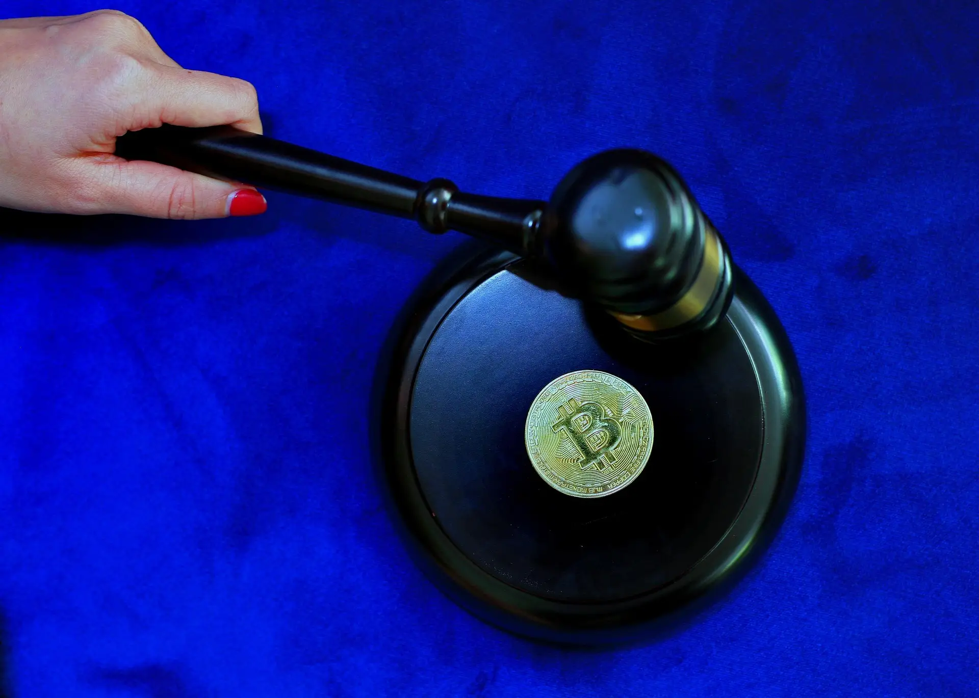 A judge's gavel and block with a bitcoin token resting on the block